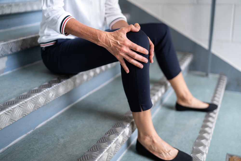 A mature woman is sitting on the staircase after a slip and fall accident