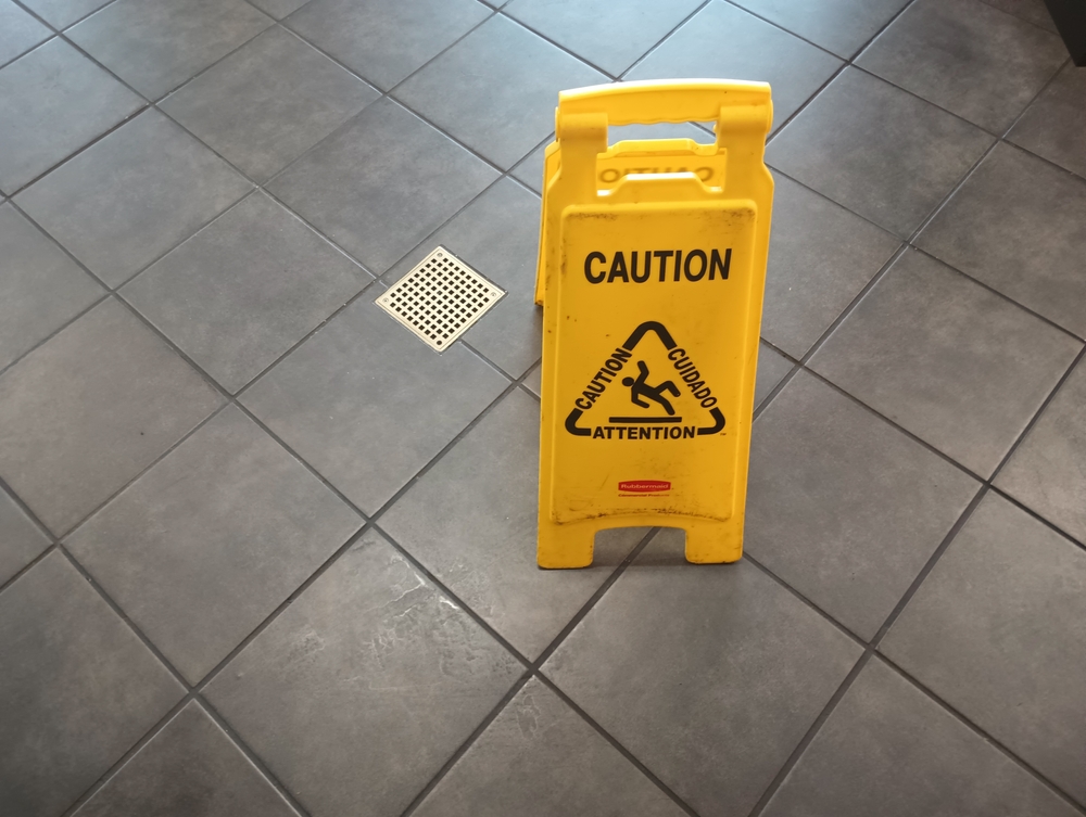A yellow caution wet floor sign on a tile floor.
