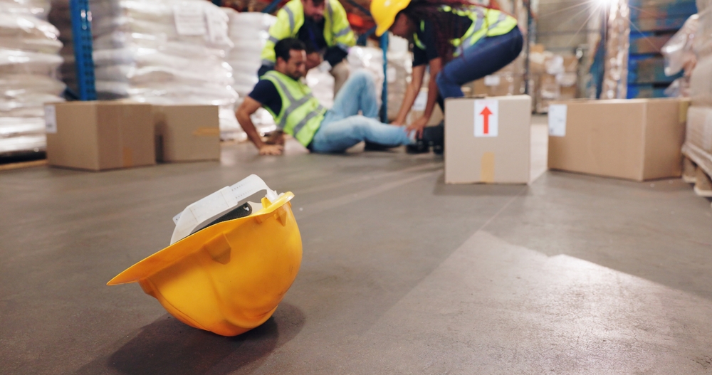 A man had an accident and fell in a warehouse while wearing a hardhat for delivery.